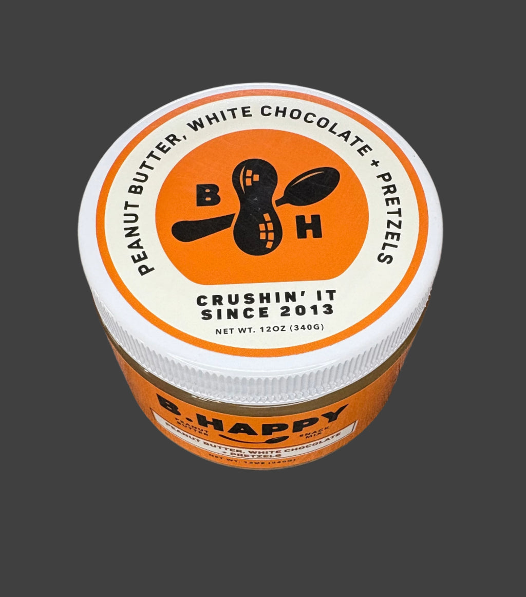 Jar of B. Happy peanut butter with white chocolate and pretzels on a wooden surface