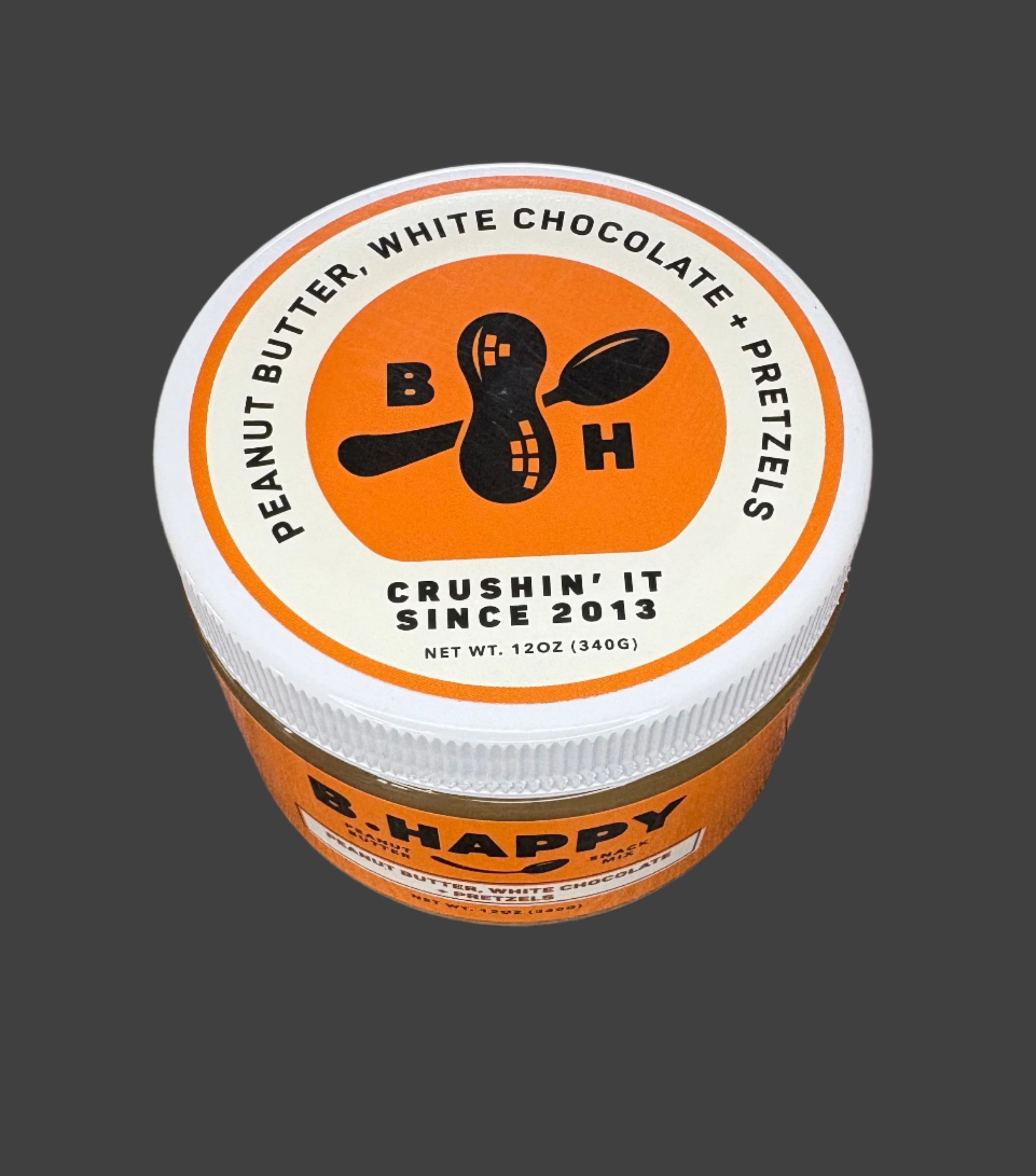 Jar of B. Happy peanut butter with white chocolate and pretzels on a wooden surface