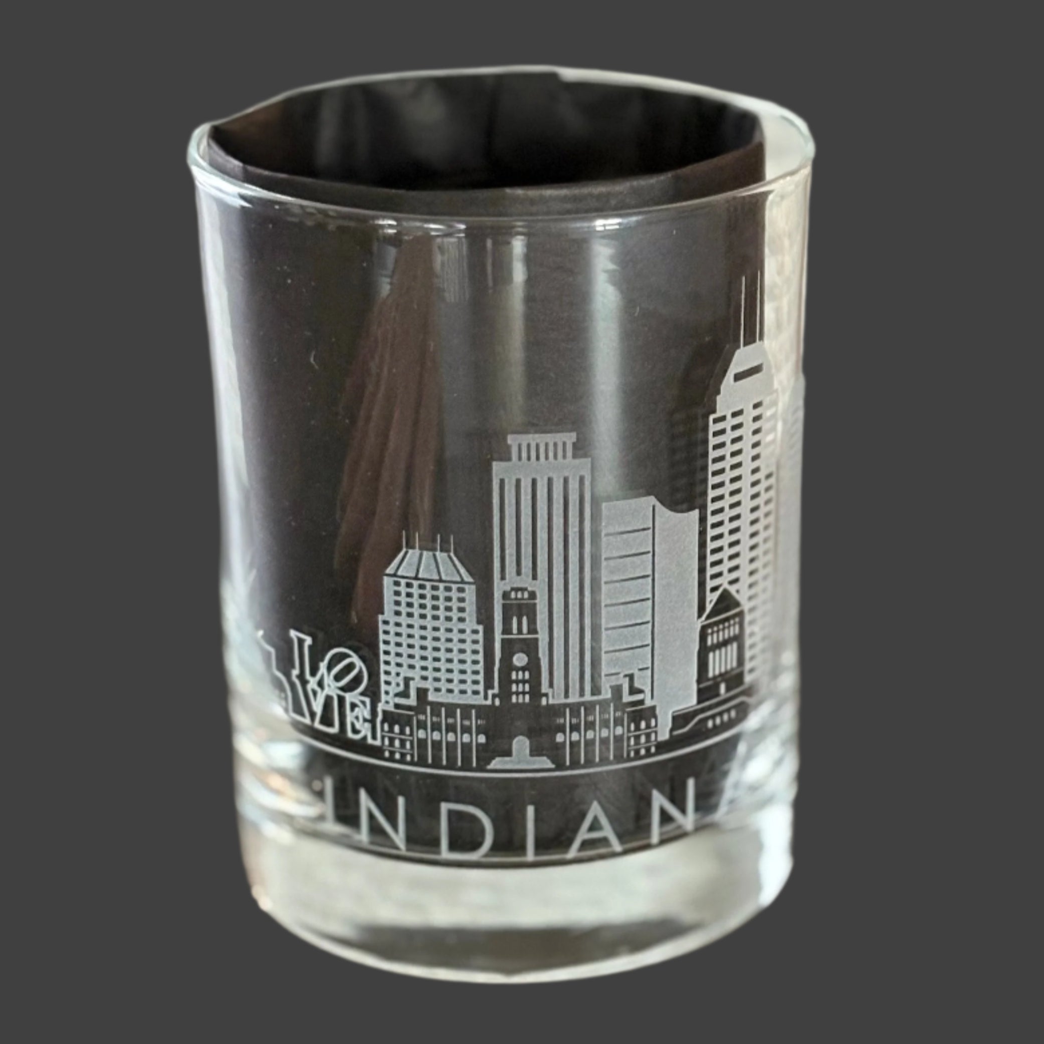 Rocks gass with Indianapolis city scape engraving on a wooden surface