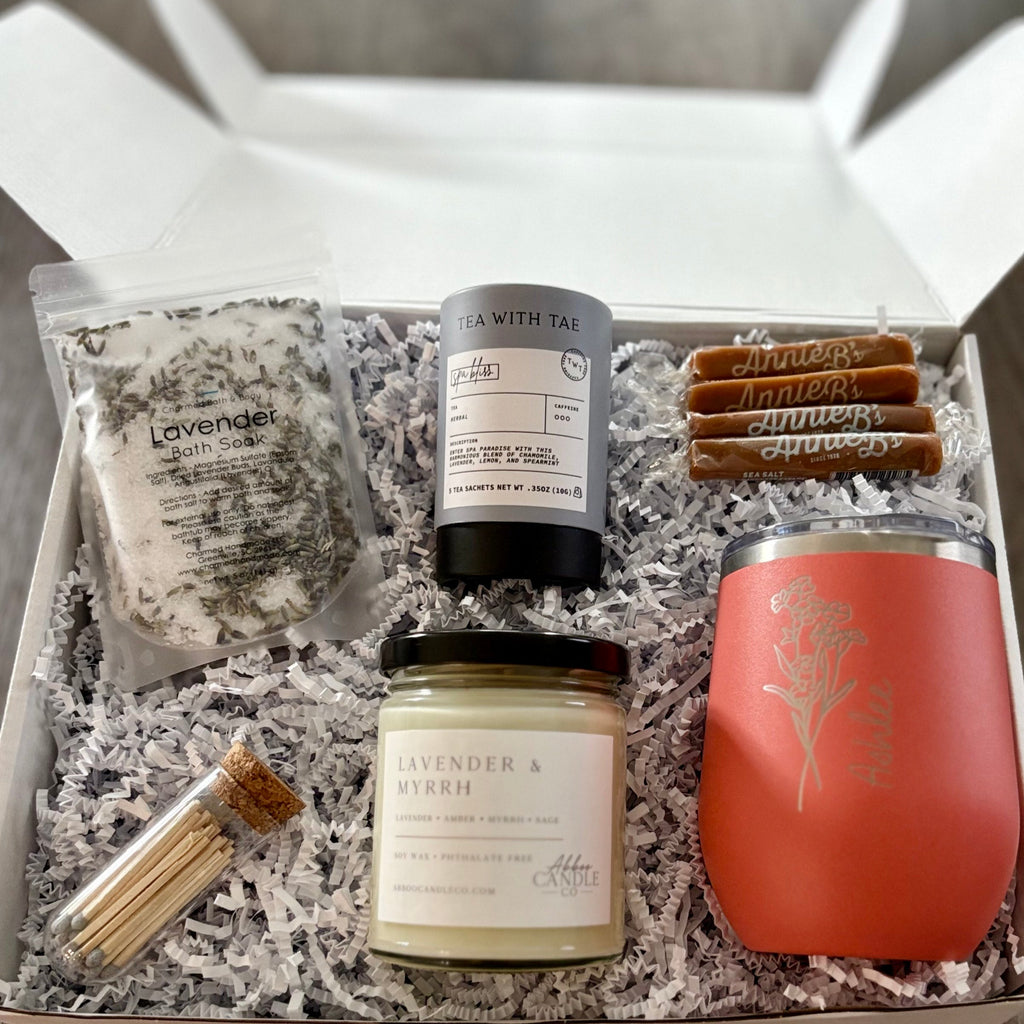 Gift box with lavender soap, candle, and other items on a wooden surface